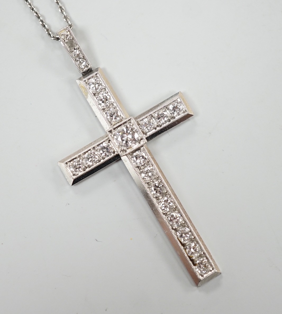 A white metal(stamped platin) and diamond set cross pendant, overall 46mm, on a white metal chain, 70cm, gross weight 12.1 grams
